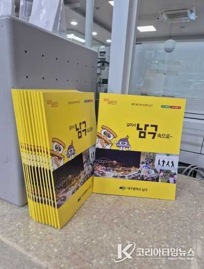 전입신고하는 주민에게 전입자를 위한 남구 안내서를 건네주고 있다.